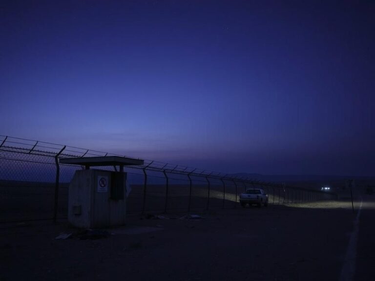 Flick International A desolate border landscape with a rusty barbed wire fence and abandoned personal belongings symbolizing the struggles of immigration.