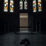 Flick International Dimly lit church interior with stained-glass windows and empty pew