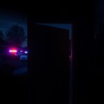 Flick International A suburban home at night with police lights illuminating the scene, depicting vulnerability.