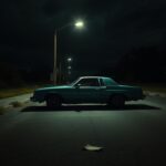 Flick International Dimly lit deserted street featuring a teal late-model Buick Skylark parked under a flickering streetlight