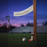 Flick International A lacrosse stick and ball resting against a goalpost on a dusk-lit field memorializing Dylan Veselic