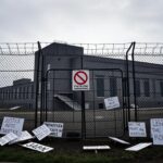 Flick International ICE detention facility in Newark, New Jersey, surrounded by barbed wire and a 'No Trespassing' sign