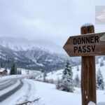 Flick International Rugged mountain landscape at Donner Pass in winter showing heavy snowfall and a weathered signpost.