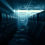 Flick International Dimly lit airplane interior with an empty row of seats and a slightly askew middle seat.