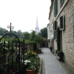 Flick International Serene Parisian street with a charming wrought-iron gate and blooming flowers