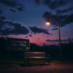 Flick International Dark urban landscape at dusk with cracked road sign and empty park bench