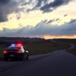Flick International Black sedan with flashing police lights in a tranquil Missouri countryside at dawn