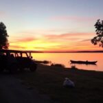 Flick International A serene sunset over Lake Norman with an empty Jeep Wagoneer parked on the roadside
