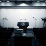 Flick International Dimly lit press briefing room with empty chairs and a large podium bearing the presidential seal