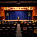 Flick International Empty auditorium stage with a podium and protest signs for 'Know Your Rights' event
