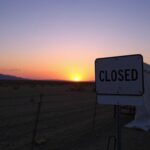 Flick International A weathered 'Closed' sign near a soft-sided processing tent at the U.S.-Mexico border