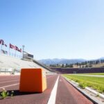 Flick International Vibrant California track and field stadium with empty bleachers and banners promoting girls' sports.