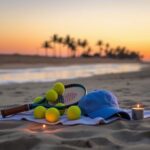 Flick International Tennis equipment and graduation cap resting on a beach towel