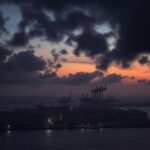 Flick International Aerial view of Hodeidah port city at dusk displaying ominous clouds and silhouette of port infrastructure