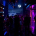 Flick International Dimly lit upscale nightclub with patrons mingling
