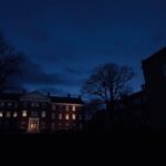 Flick International A solitary university campus at twilight with Tufts University brick building illuminated by dusk light