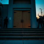 Flick International Government building entrance in Los Angeles during riots, featuring armed National Guard troops and graffiti art