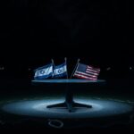 Flick International Night scene in park with empty circular table and contrasting flags of Israel and the United States