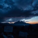Flick International Dark, dramatic landscape of Boulder, Colorado with protest signs and the Flatirons in the background