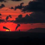 Flick International Silhouette of a war-torn city skyline with smoke against a dusky sky