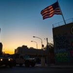 Flick International Marines' vehicles contrasting with urban protest symbols in Los Angeles