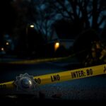 Flick International Dark, moody scene of a suburban street at dawn with police tape and a badge