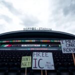 Flick International A dramatic exterior view of SoFi Stadium with protest signs against ICE in the foreground