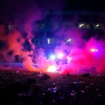 Flick International Scene of chaos and unrest outside an ICE building in Portland, showcasing shattered glass and smoke