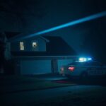 Flick International Night-time scene of a suburban home in Brooklyn Park, Minnesota, damaged by gunfire with shattered windows and police presence