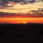 Flick International Dramatic desert landscape at sunset illustrating ongoing conflict with military equipment