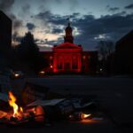 Flick International Shattered Molotov cocktail and protest signs near Boulder County courthouse at twilight