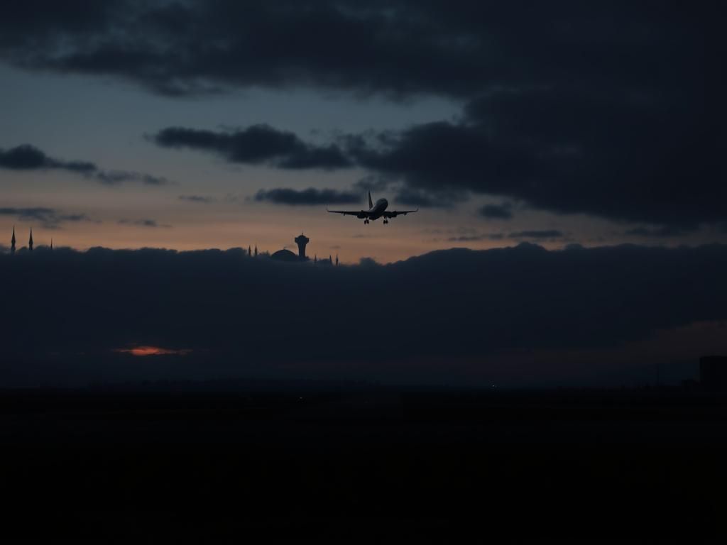 Flick International Silhouette of an airplane taking off against a backdrop of dark clouds symbolizing tension and uncertainty