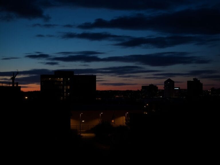 Flick International Twilight scene of a Minnesota cityscape with silhouettes of a police station and jail